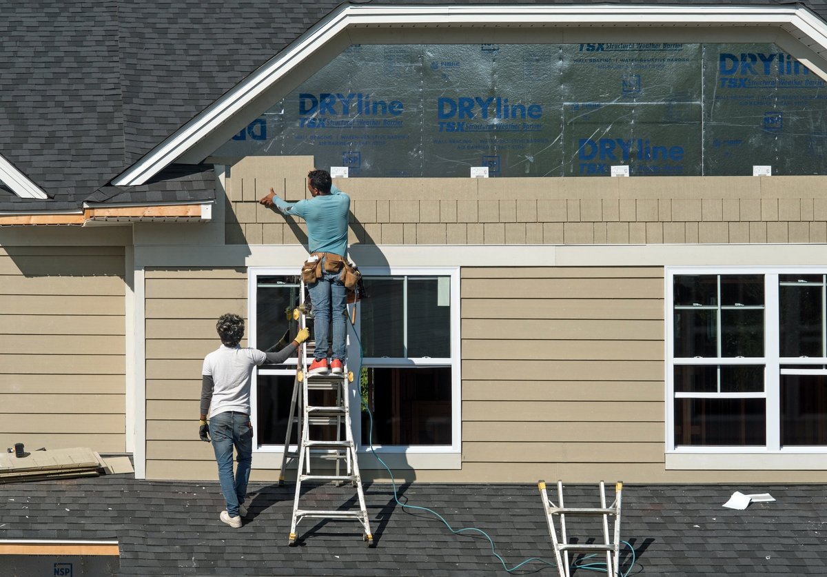 Construction workers installing shake siding